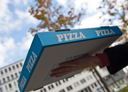 Ein Lieferant mit einem Pizzakarton