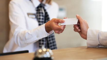 Receptionist giving key card to businesswoman at hotel front desk
