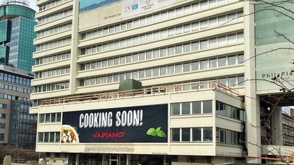 Außenansicht eines Gebäudes an dem ein großes Banner hängt auf dem steht Cooking Soon! Vapiano
