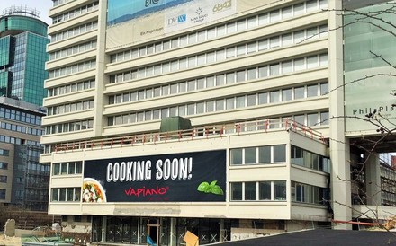 Außenansicht eines Gebäudes an dem ein großes Banner hängt auf dem steht Cooking Soon! Vapiano