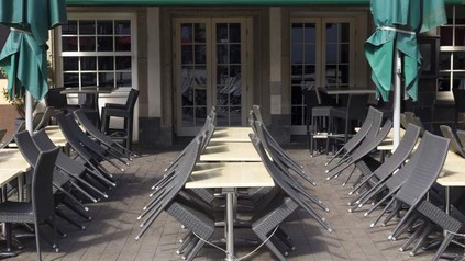 Ein geschlossener Außenbereich eines Restaurants mit an die Tische gelehnten Stühlen