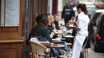 Kellnerin bringt Getränke an Tisch