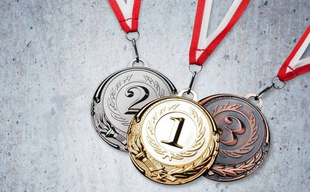 Eine goldene, eine silberne und eine bronzene Medaille an roten Bändern