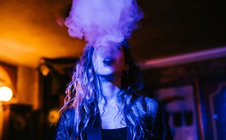 Junge Frau raucht in einem Nachtlokal