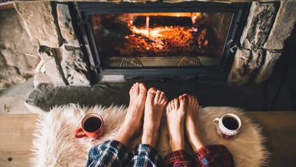 Nackte Zehen von Frau und Mann vor Kamin