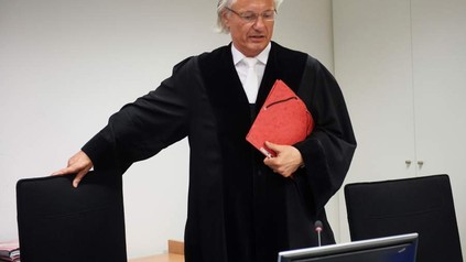 Richter Manfred Winterscheidt in Richterrobe setzt sich auf einen Stuhl im Oberlandesgericht