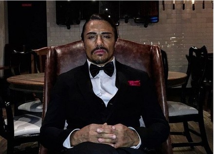 Nusret Gökçe mit Anzug auf Sessel