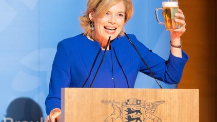 Julia Klöckner am Rednerpult mit einem Bier in der Hand
