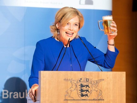 Julia Klöckner am Rednerpult mit einem Bier in der Hand