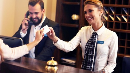 Zwei freundliche Mitarbeiter bedienen einen Kunden an der Hotelrezeption