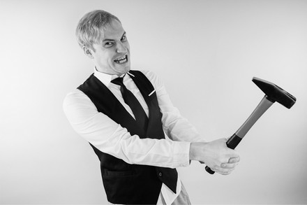 Kellner mit Hammer in der Hand und verrücktem Gesichtsausdruck