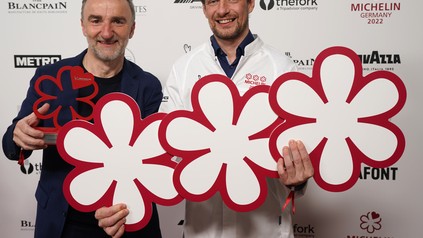 Thomas Schanz und Johannes King halten ihre Michelin-Sterne vor einer Logowand hoch