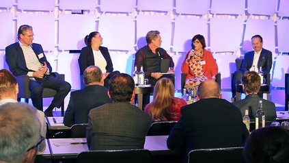 Eine Gruppe Teilnehmer diskutiert auf einem Podium