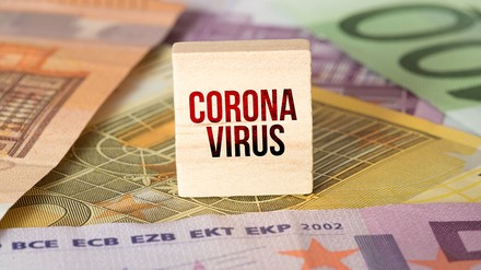 Euro Geldscheine und ein Holzwürfel mit der Aufschrift „Coronavirus“