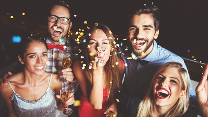 Eine Gruppe feiernder Menschen mit Sekt und Konfetti in der Hand