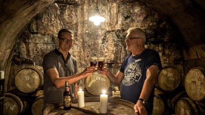 Zwei Männer stoßen in der Schatzkapelle der Miltenberger Brauerei Faust fröhlich an