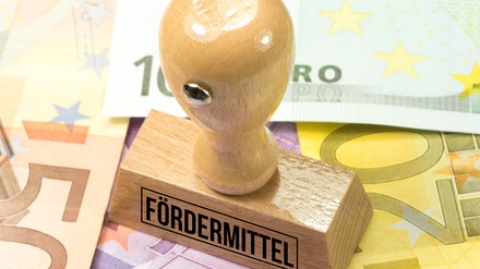 Stempel mit der Aufschrift Fördermittel auf Geldscheinen