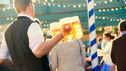 Ein Kellner im Bierzelt, der mit einigen Maß Bier in der Hand durch die Besucherschar läuft