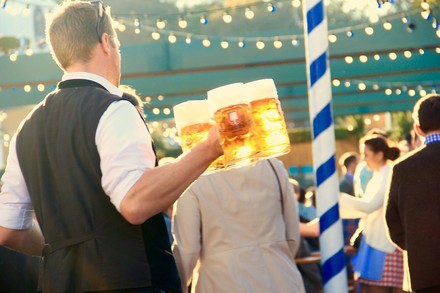 Ein Kellner im Bierzelt, der mit einigen Maß Bier in der Hand durch die Besucherschar läuft