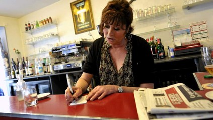 Frau an Theke schreibt auf einen Zettel