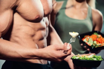 Ein Mann mit Sixpack isst Salat