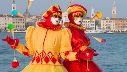 Zwei bunt maskierte Gestalten posieren in Venedig von Eis umgeben