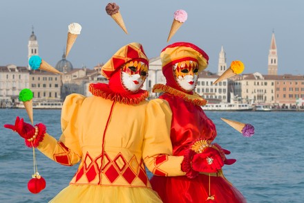 Zwei bunt maskierte Gestalten posieren in Venedig von Eis umgeben