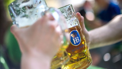 Zwei Personen stoßen mit Maßkrügen vom Hofbräuhaus München an