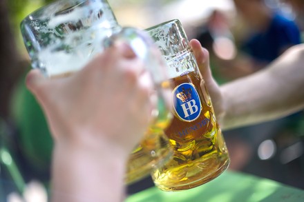 Zwei Personen stoßen mit Maßkrügen vom Hofbräuhaus München an
