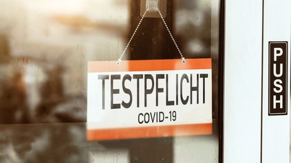 Testpflicht, translated: - mandatory testing sign hangs on the door of a store