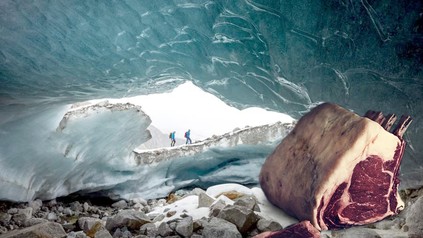 In einer Gletscherhöhle an der zwei Bergsteiger vorbeilaufen liegt ein großes Stück Fleisch
