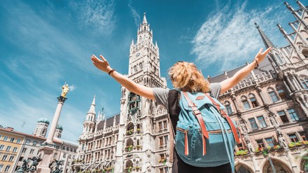 A girl tourist traveler enjoys a Grand view of the Gothic building of the Old town Hall in Munich. Sightseeing and exploration of Germany concept