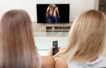 Zwei Frauen sehen sich muskulösen Mann im Fernsehen an