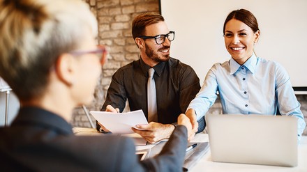 Eine junge Frau sitzt beim Vorstellungsgespräch zwei Recruitern/HR Managern gegenüber