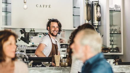 Lächelnder Barista hinter der Theke eines Coffeeshops