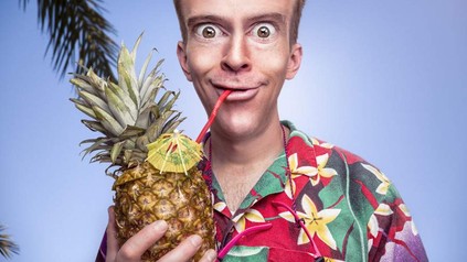 Frau in Hawaii-Hemd trinkt aus Ananas