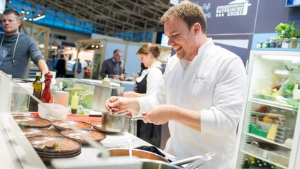 An einem Messestand auf der Food & Life bereitet ein Koch ein Gericht zu