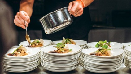 Ein Koch verteilt Soße auf Tellern mit Gerichten