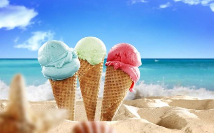 Drei Waffeln mit Eis im Sand vor blauem Meer
