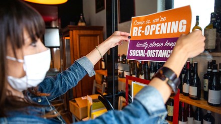 Frau hängt Re-Opening-Schild an die Café-Tür