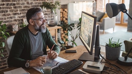 Mann sitzt im Homeoffice am Computer und führt mit mehreren Leuten eine Videokonferenz