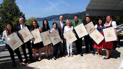 Roland Heitzeneder mit langjährigen Mitarbeitern und Lehrlingen, die ihre Urkunden hochhalten