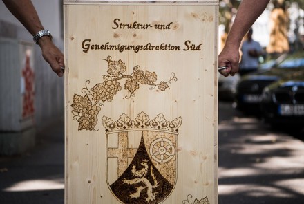 Zwei Hände tragen einen Holzkasten mit der Aufschrift Struktur- und Genehmigungsdirektion Süd