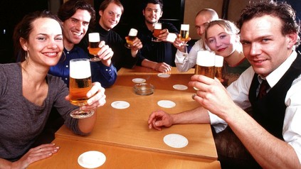Ein paar fröhliche Gäste mit Bier in den Händen an einem gemeinsamen Tisch