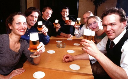 Ein paar fröhliche Gäste mit Bier in den Händen an einem gemeinsamen Tisch