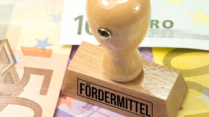 Stempel mit der Aufschrift "Fördermittel" steht auf Euroscheinen