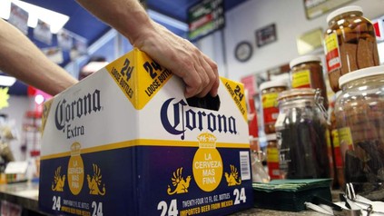 Eine Person stellt eine Box mit Corona Bier auf eine Theke