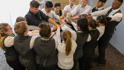 Eine Gruppe junger Gastronomien steckt die Hände zusammen als Zeichen der Gemeinschaft