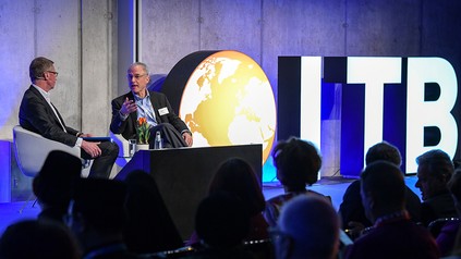 Zwei Männer führen auf einer Bühne vor Publikum ein Interview