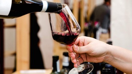 Eine Hand hält ein Weinglas in das Wein gegossen wird